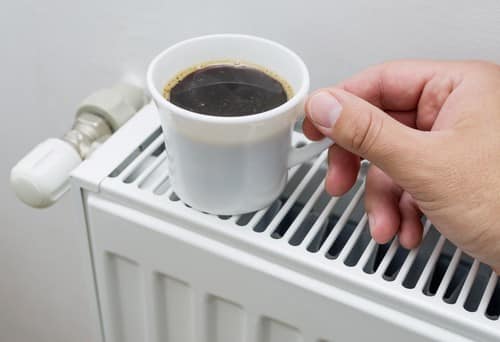 Chauffagiste Apt - main qui pose une tasse de café sur un chauffage