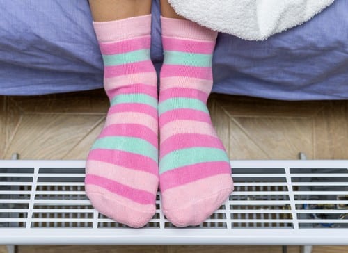 Chauffagiste Bollène - pieds avec chaussettes posés sur un chauffage