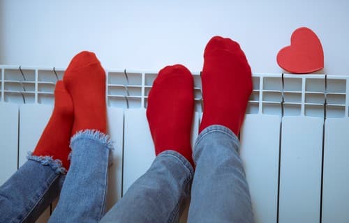 Chauffagiste Canet-en-Roussillon - pieds avec chaussettes rouges posés sur un chauffage