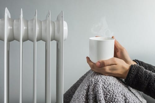 Chauffagiste Douarnenez - les bons artisans - femme qui se réchauffe près de son radiateur