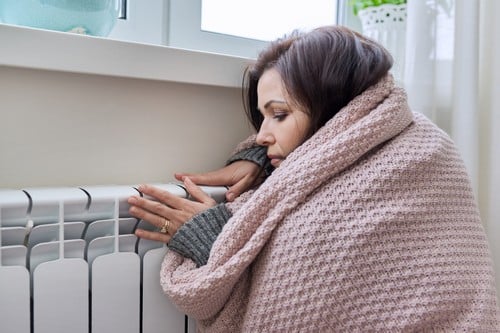 Chauffagiste La Chapelle-Saint-Luc - les bons artisans - femme qui se réchauffe contre un radiateur