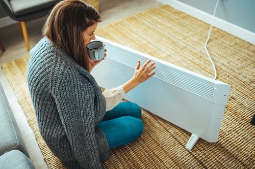 Chauffagiste Lingolsheim - les bons artisans - femme qui se réchauffe près d'un radiateur électrique