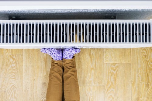 Chauffagiste Longwy - les bons artisans - pieds contre un radiateur pour se réchauffer