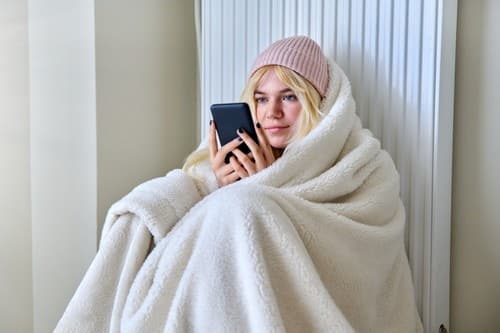 Chauffagiste Pornichet - femme avec couverture posée devant un chauffage