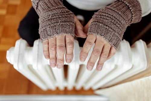 Chauffagiste Romilly-sur-Seine - les bons artisans - dame qui réchauffe ses mains sur un radiateur