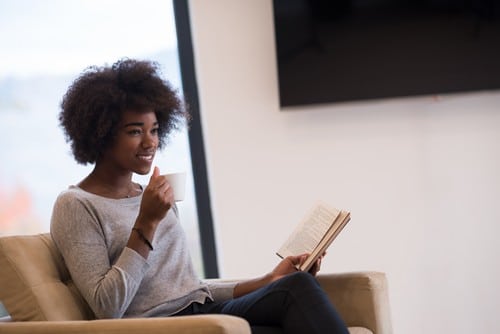 Chauffagiste Sablé-sur-Sarthe - femme qui lit un livre et qui tient une tasse dans une pièce chauffée