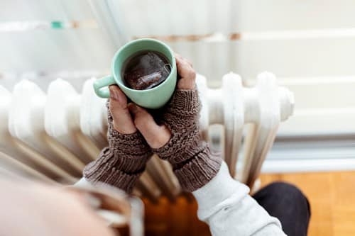 Chauffagiste Saint-Avé - les bons artisans - femme qui se réchauffe avec son radiateur