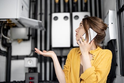 Chauffagiste Villetaneuse - femme au téléphone avec chauffe eau ne marche plus