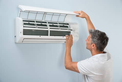 Climatisation Colombes - homme qui règle un climatiseur au plafond