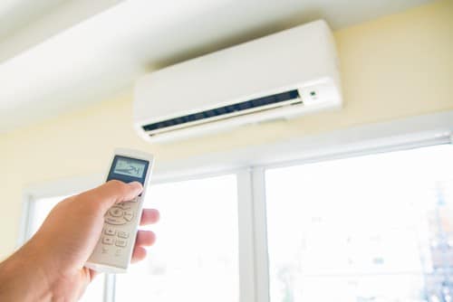 Climatisation Issy-les-Moulineaux - main d'un homme qui tient une télécommande pour régler un climatiseur au plafond