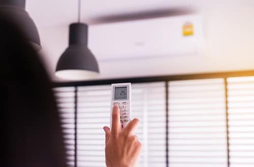 Climatisation Levallois-Perret - mains d'une femme qui tient une télécommande pour climatiseur