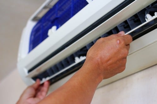 Climatisation Paris 6 - mains qui règlent un climatiseur