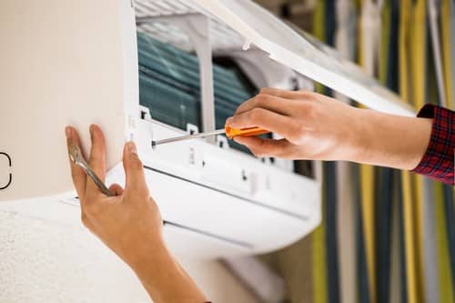 Climatisation Puteaux - mains d'un homme qui règle un climatiseur