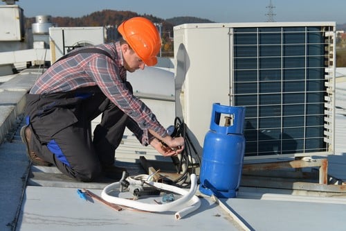 Climatisation Suresnes - homme qui règle un climatiseur en extérieur