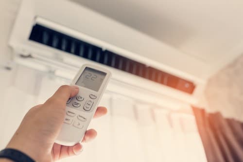 Climatisation Vigneux-sur-Seine - main d'un homme qui tient une télécommande pour régler climatiseur