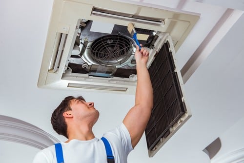 Climatisation Villejuif - homme qui règle un climatiseur au plafond