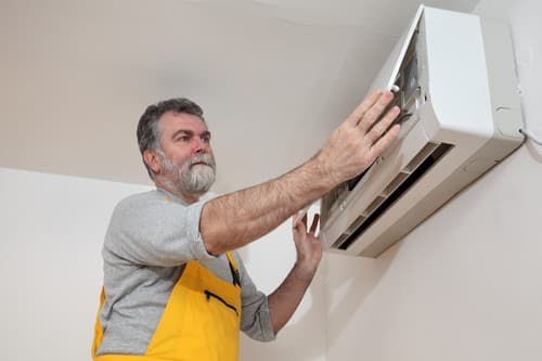 Climatisation Yerres - homme qui règle un climatiseur au plafond