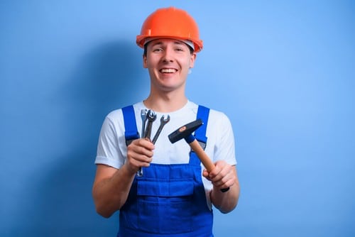 Electricien Bures-sur-Yvette - homme qui tient des outils devant un mur bleu