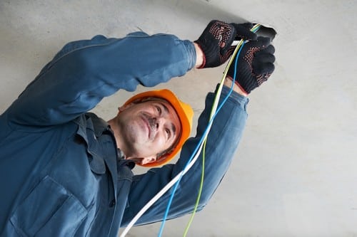 Electricien Saint-Cyr-l'Ecole - homme qui installe un appareil électrique au plafond