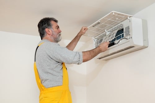 climatisation Paris 10 - homme qui règle un climatiseur au plafond