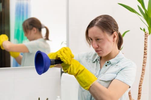 Plombier Carrières-sur-Seine - femme qui tient un déboucheur devant son lavabo