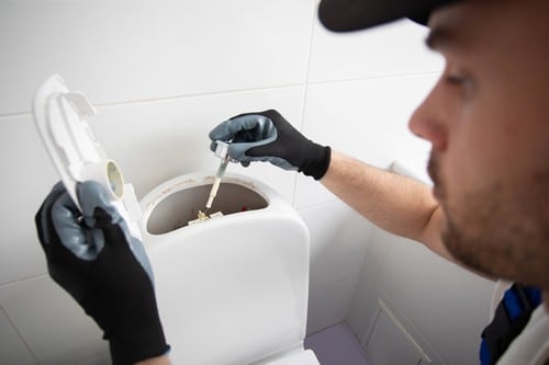 Plombier Montmagny - homme qui règle un cabinet de toilette