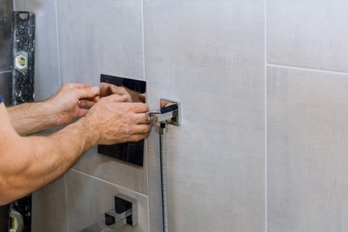 Plombier Saint-Leu-la-Forêt - mains d'un homme qui règle une douche