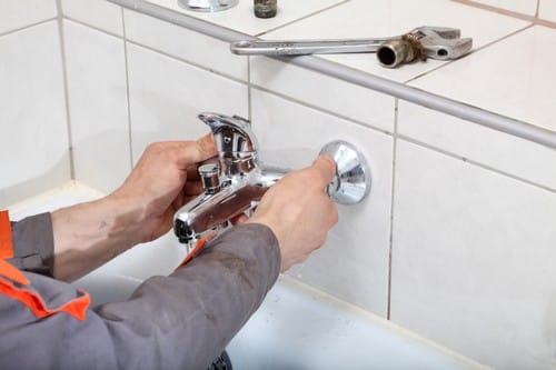 Plombier Villecresnes - mains d'un homme qui règle un robinet