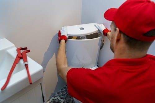 Plombier Voisins-le-Bretonneux - homme qui règle un cabinet de toilette