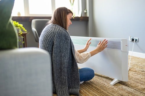 chauffagiste Claye-Souilly - une femme se réchauffe devant un radiateur électrique