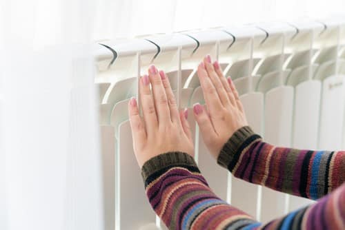 chauffagiste Morangis - une femme se réchauffe les mains devant le radiateur