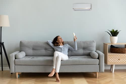 climatisation Le Blanc-Mesnil - une femme assise dans son canapé allume sa clim