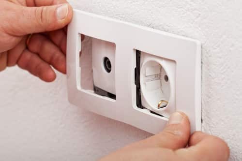 électricien Quetigny - un artisan électricien pose une prise électrique pairée à une prise téléphonique