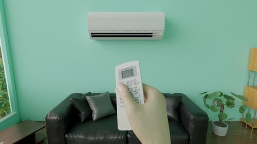 Climatisation Andernos-les-Bains - main qui tient une télécommande pour régler un climatiseur