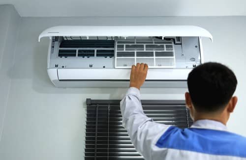 Climatisation Gradignan - homme qui règle un climatiseur au plafond