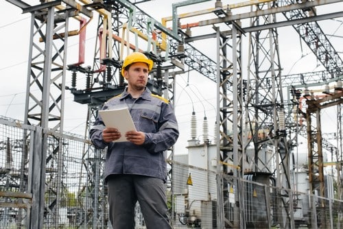 Electricien Mayenne - homme devant des grues et des installations