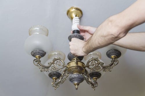 Électricien Soisy-sous-Montmorency - mains d'un homme qui règle une lampe au plafond