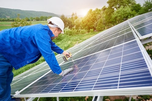 Electricien Vaux-le-Pénil - homme qui installe des panneaux solaires en extérieur