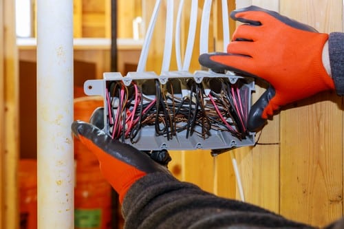 Electricien Villecresnes - mains qui règlent des fils électriques