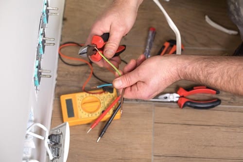 Electricien Voisins-le-Bretonneux - mains d'un homme qui règle une prise murale