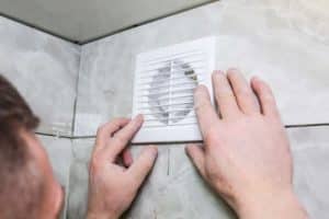 Un artisan pose une VMC dans une salle de bains