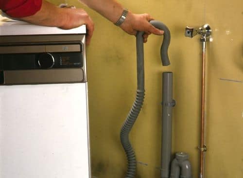 Un artisan installe un conduit d'évacuation de machine à laver