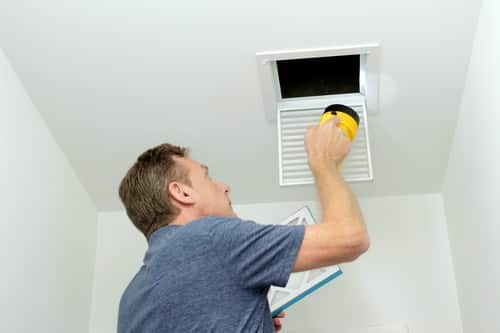 Climatisation Bondoufle - homme qui règle un climatiseur au plafond
