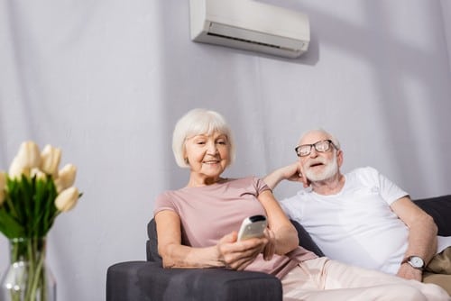 Climatisation Bures-sur-Yvette - un couple qui est assis sur un canapé en dessous d'un climatiseur