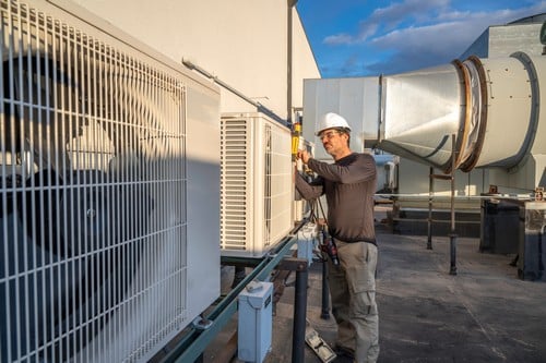 Climatisation Chassieu - homme qui règle des climatiseurs en extérieur