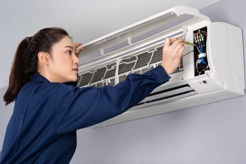 Climatisation Dardilly - femme qui règle un climatiseur au plafond