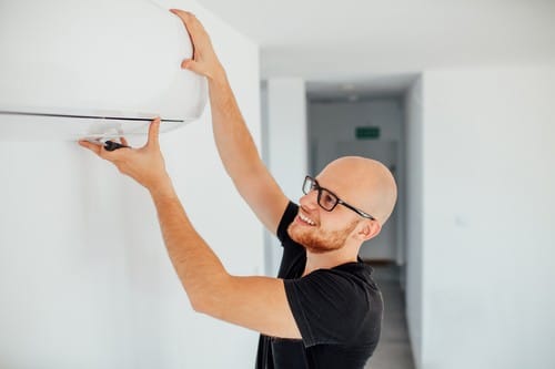 Climatisation Louvres - homme qui règle un climatiseur au plafond