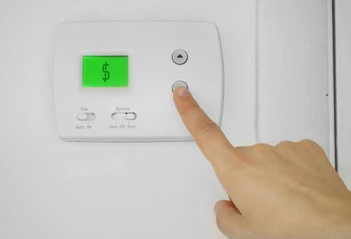 Climatisation Osny - main qui règle un bouton de climatiseur