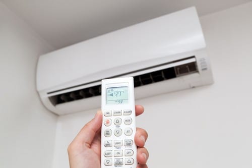 Climatisation Saint-Rémy-de-Provence - main qui tient une télécommande pour régler un climatiseur au plafond