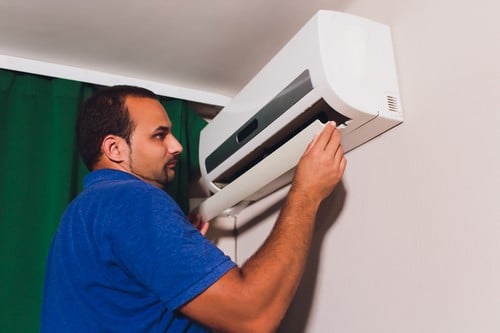 Climatisation Aussonne - homme qui règle un climatiseur au plafond